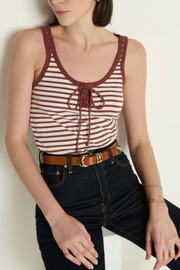 Woman wearing a striped tank top and jeans against a plain background