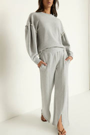 Woman wearing a gray sweatshirt and pants set on a white background