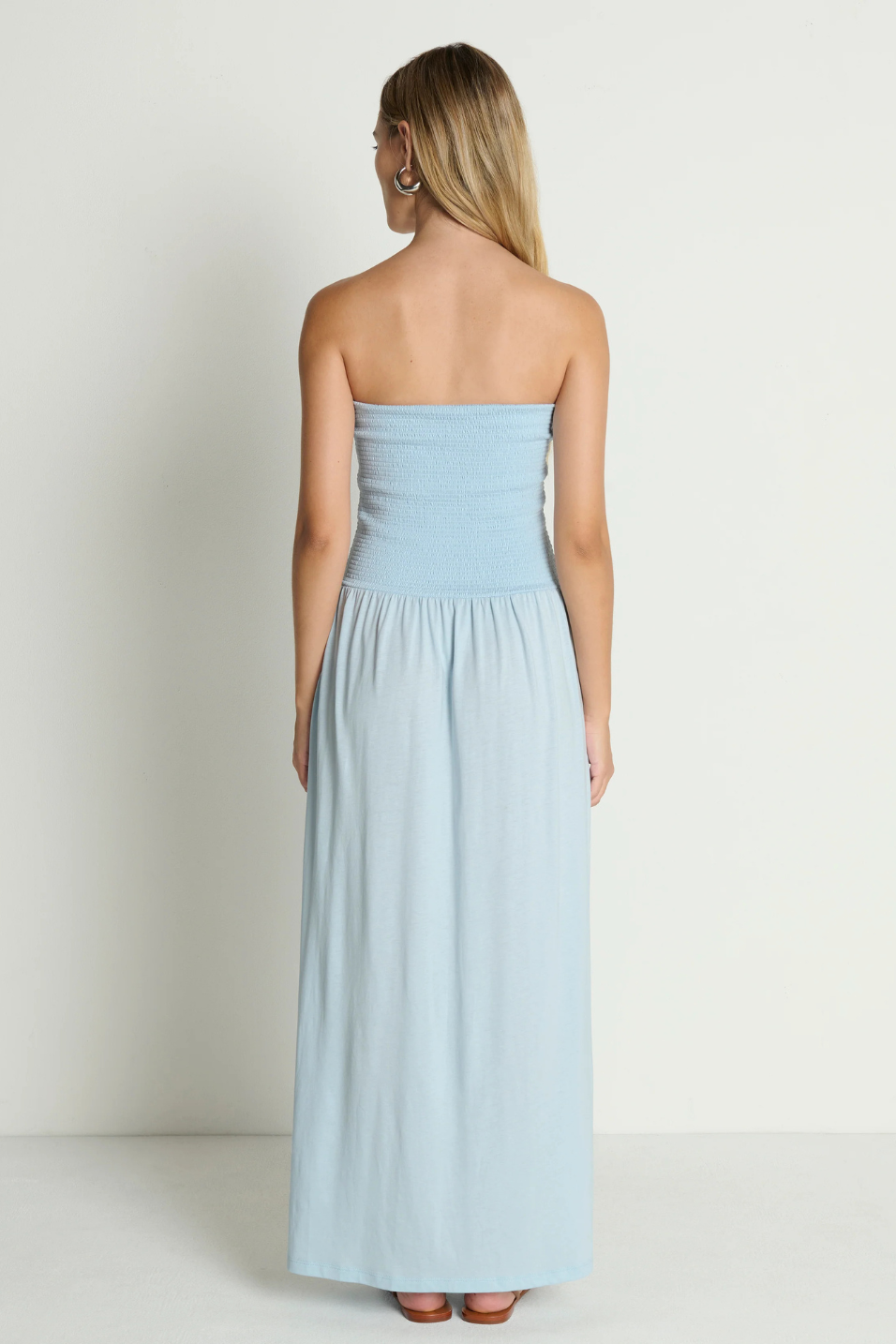 Woman wearing a light blue strapless dress against a white background