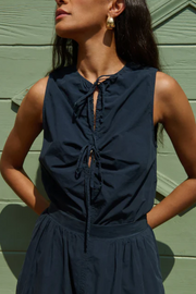 Woman wearing a navy blue sleeveless top with a green wooden background