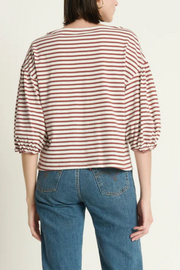 Person wearing a sabal striped shirt and blue jeans on a plain background