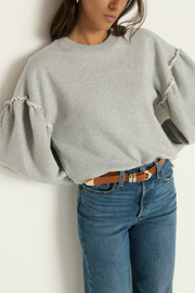 Person wearing a gray sweatshirt and blue jeans against a white background