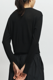 Person wearing a black long-sleeve top and black pants on a light gray background