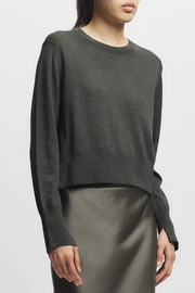 Person wearing a olive sweater and satin skirt on a white background