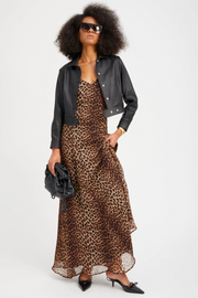 Woman wearing a leopard print dress with a black leather jacket on a white background