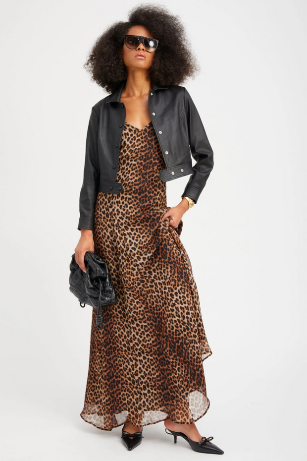 Woman wearing a leopard print dress with a black leather jacket on a white background