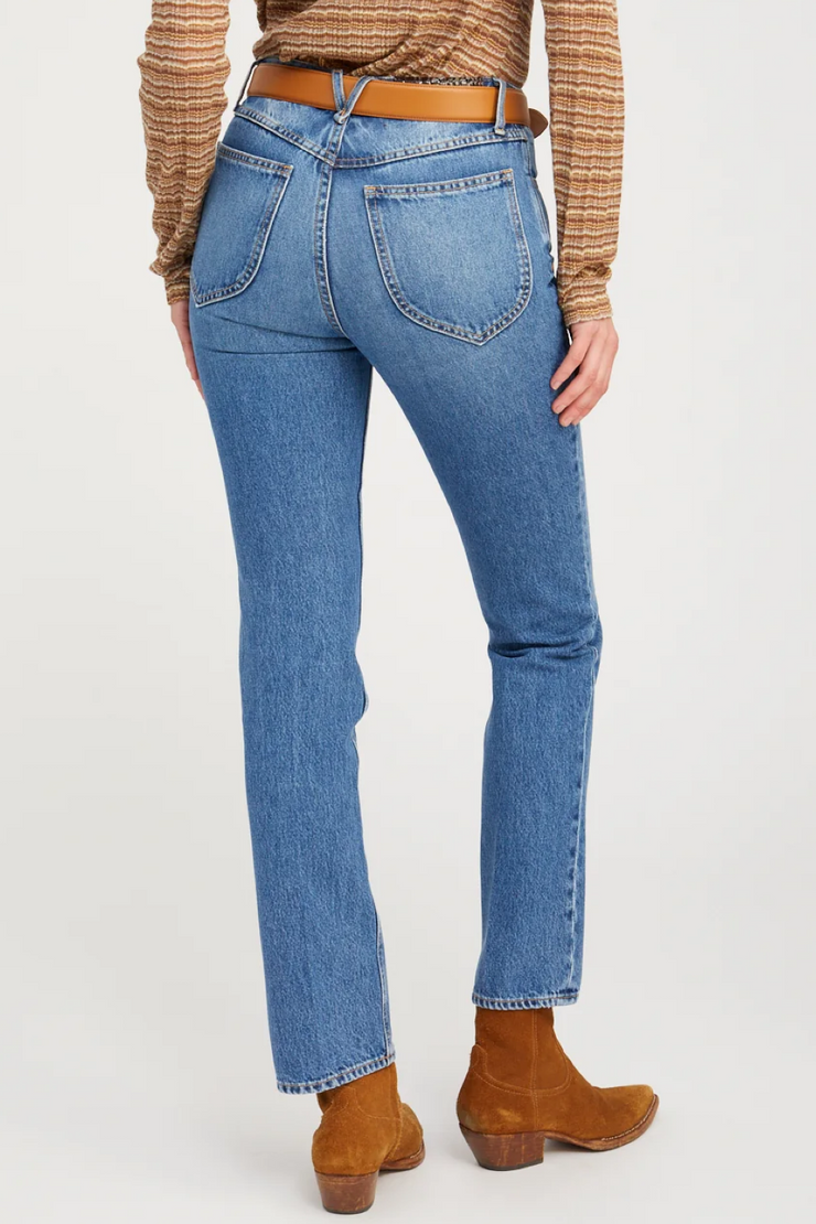 Person wearing blue jeans and brown boots on a white background