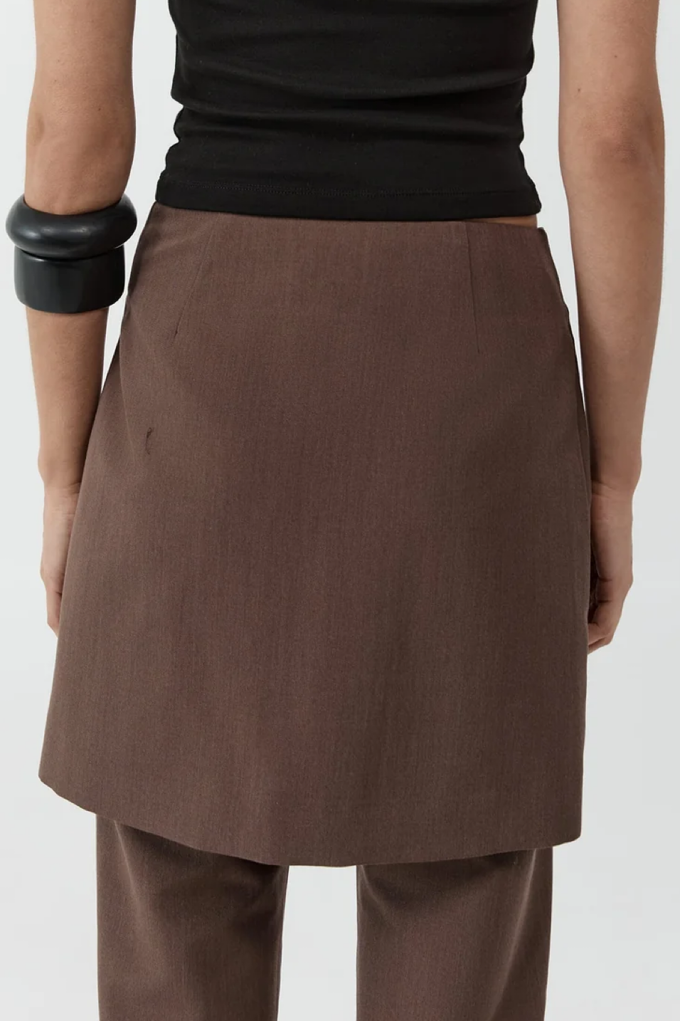 Person wearing a brown skirt and black top on a plain background