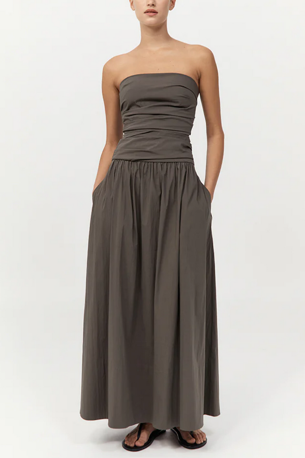 Woman wearing a strapless, long khaki dress on a white background