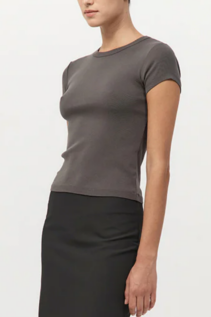 Person wearing a khaki t-shirt and black skirt on a white background