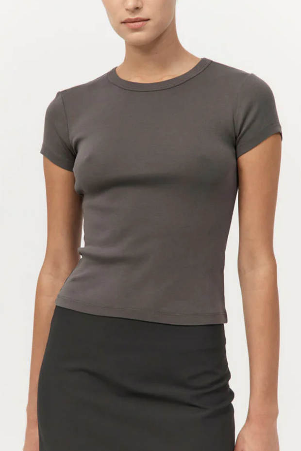 Person wearing a khaki t-shirt and black skirt on a white background