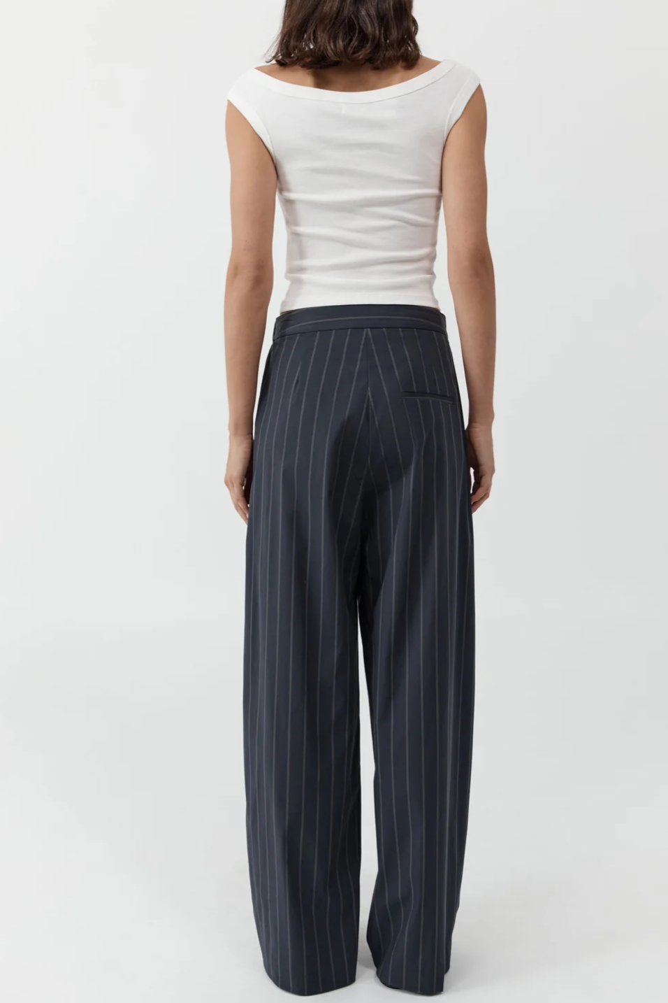 Person wearing a white top and pinstripe pants on a white background