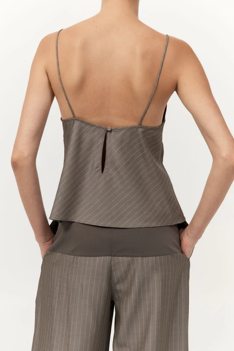 Person wearing a khaki pinstripe top and pants on a white background