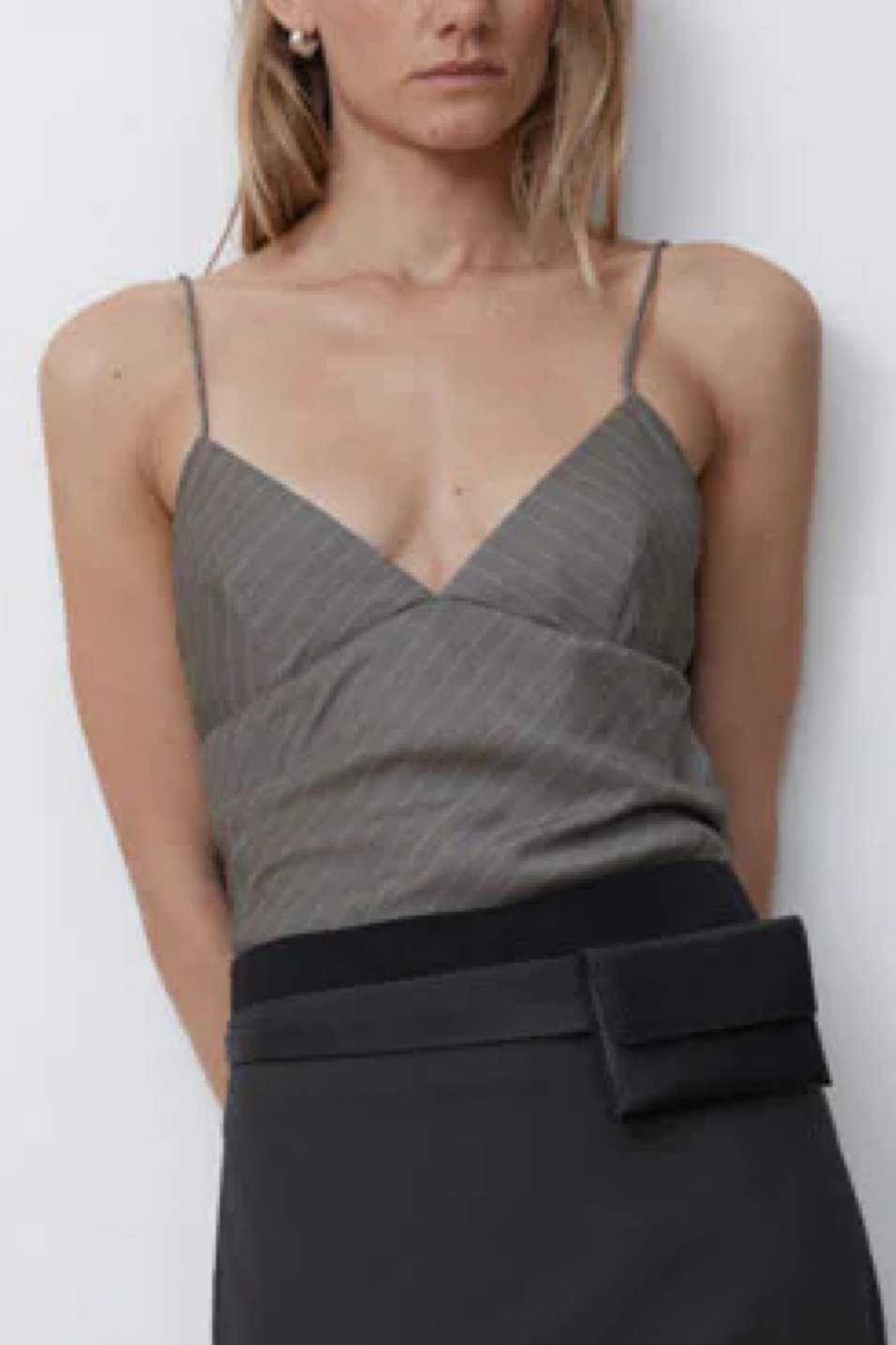 Woman wearing a khaki pinstripe top and black skirt against a white background