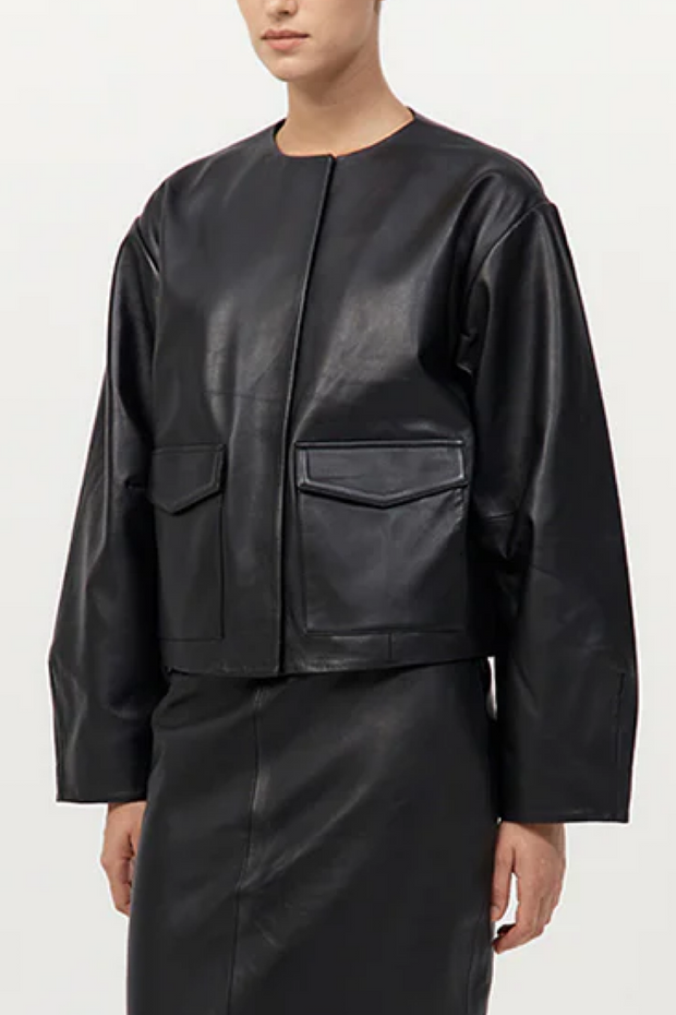 Person wearing a black leather jacket and pants on a white background