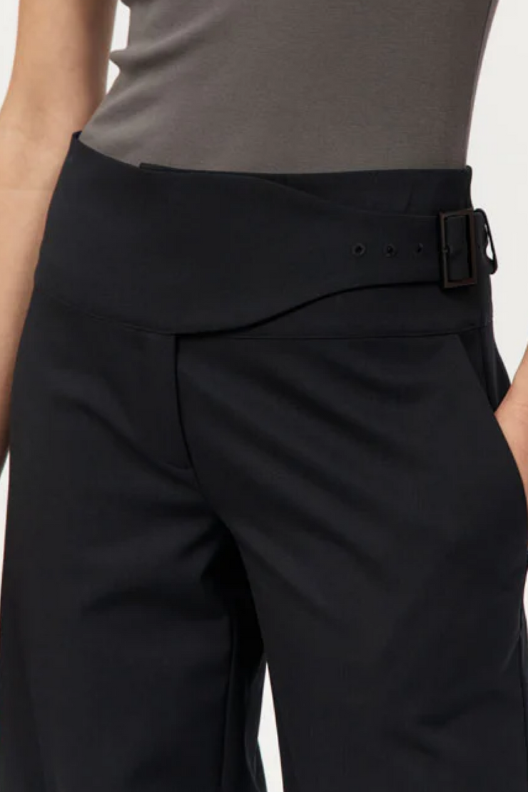 Black pants with a belt worn by a person on a plain background