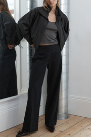 Person wearing a black outfit standing in front of a mirror.