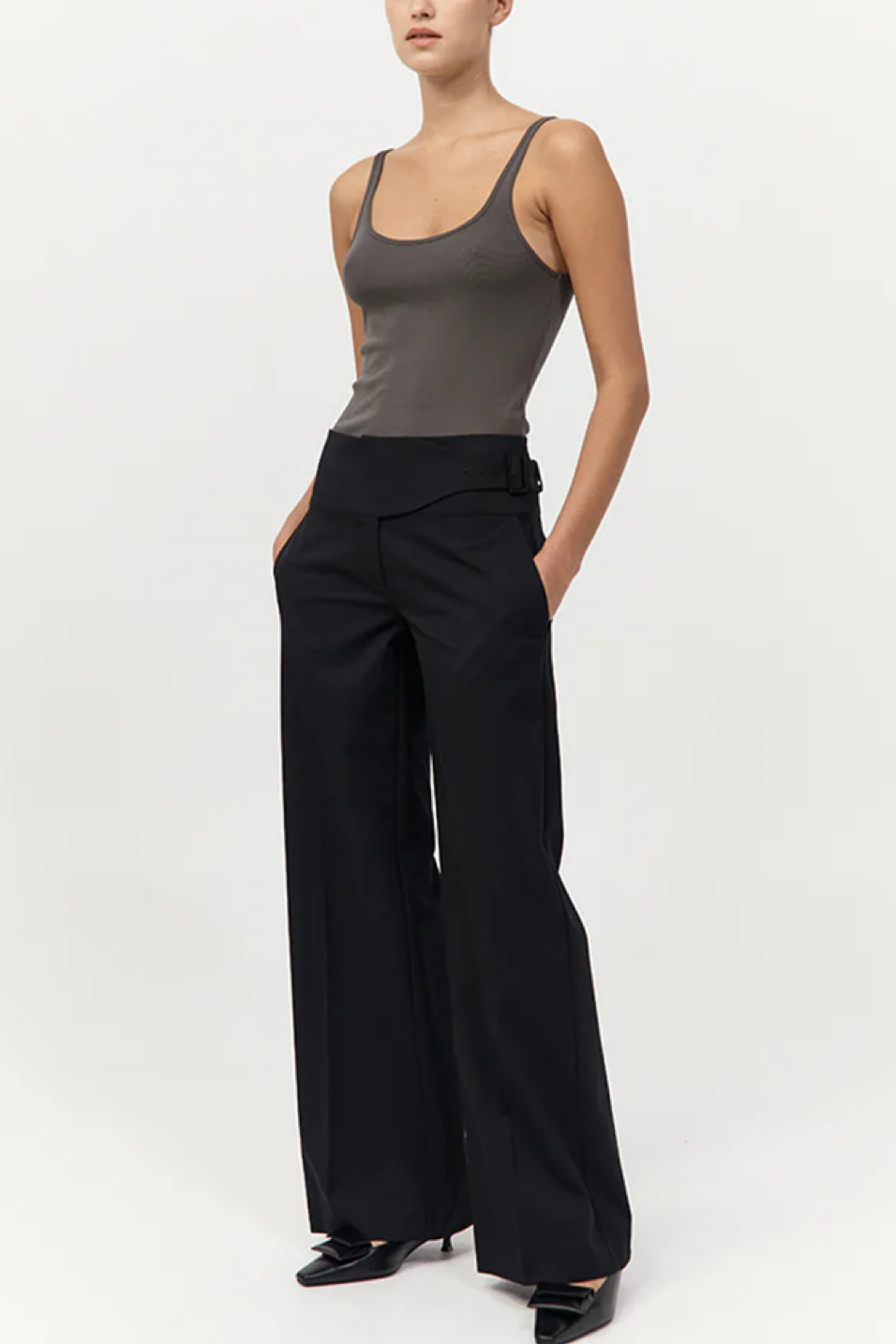 Person wearing a gray tank top and black wide-leg pants on a white background