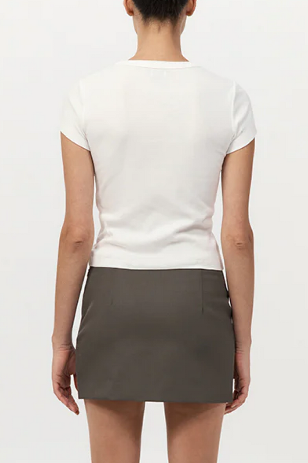Person wearing a white top and gray skirt on a plain background