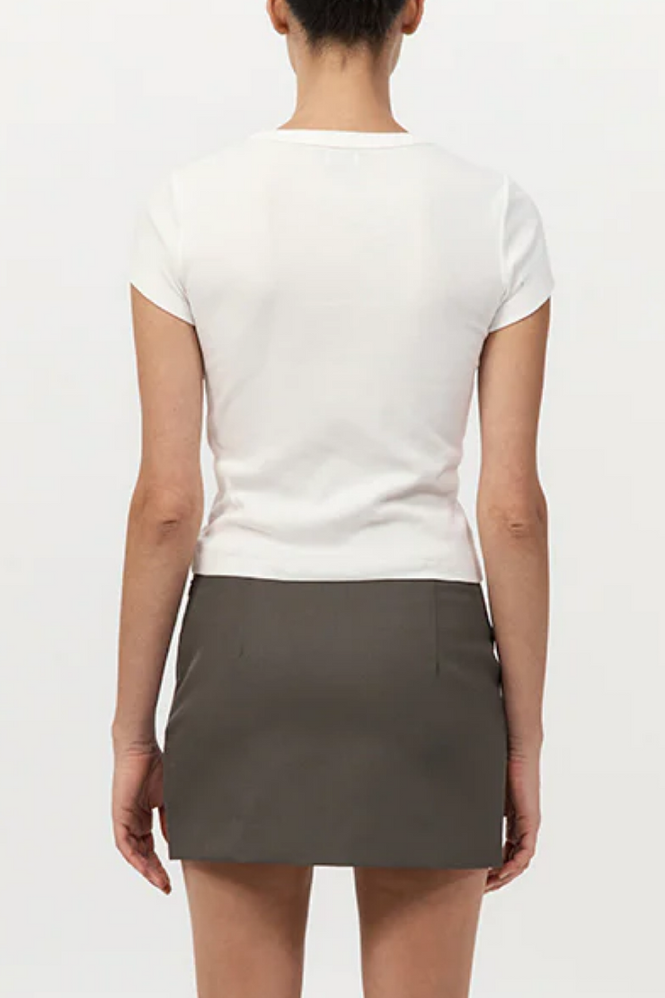 Person wearing a white top and gray skirt on a plain background