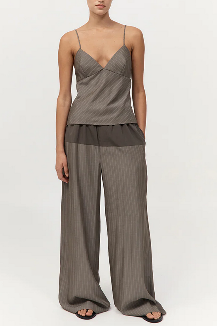 Woman wearing a khaki pinstripe top and wide-leg pants on a white background