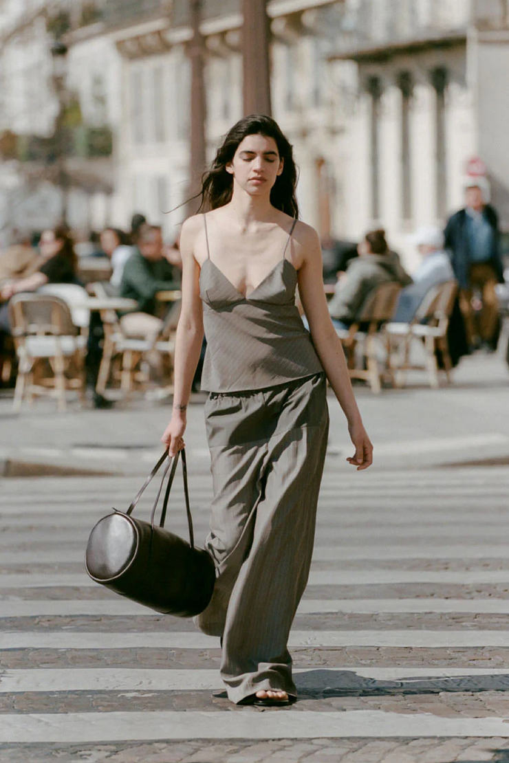 Woman walking on a city street holding a black handbag