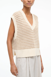 Woman wearing a beige knitted sleeveless top on a white background