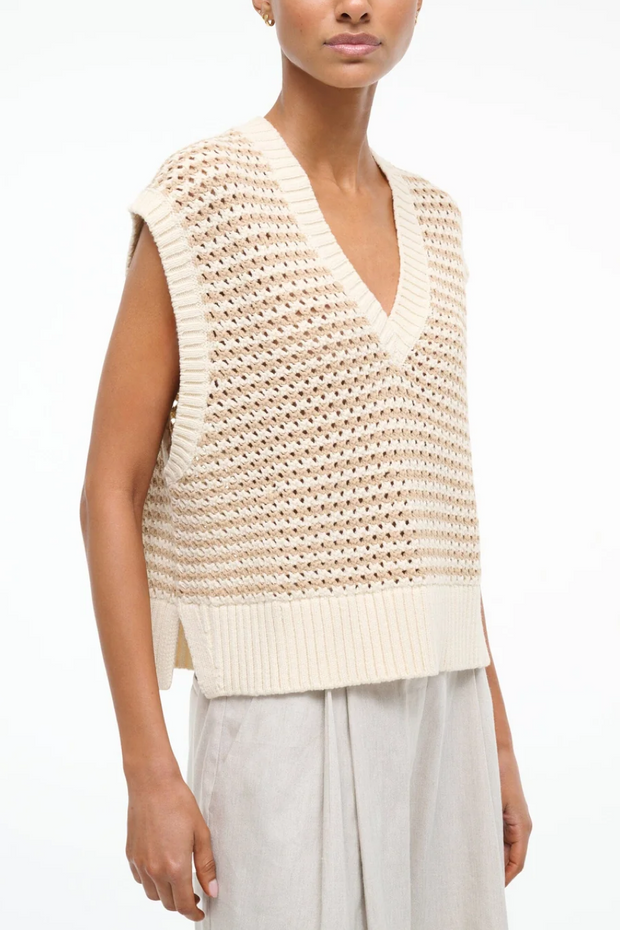 Woman wearing a beige knitted sleeveless top on a white background