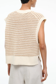 Beige knitted sleeveless top worn by a person on a white background