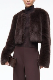 Dark brown fur jacket worn over a black turtleneck sweater on a white background
