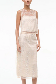 Woman wearing a two tone beaded top and skirt on a white background