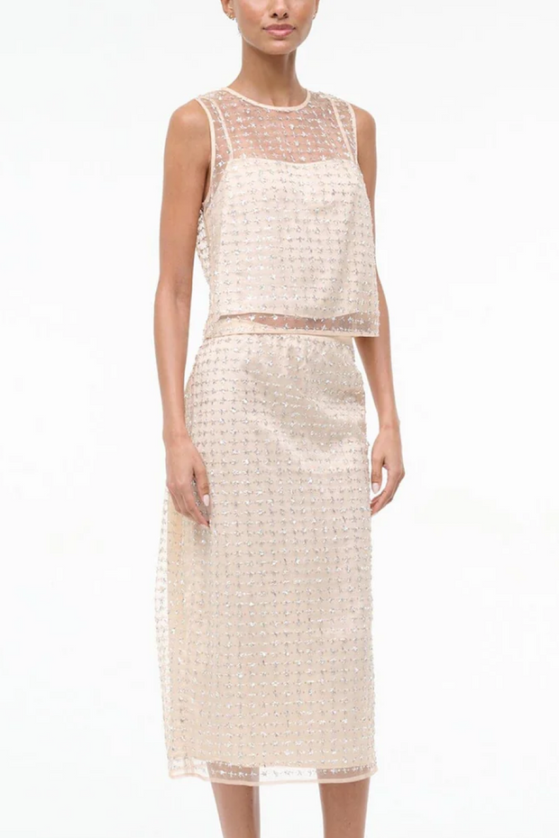 Woman wearing a two tone beaded top and skirt on a white background