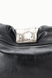 Black leather handbag with a silver 'Staud' logo on a white background