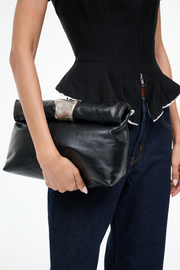 Person holding a black leather clutch with a white background