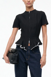 Black peplum top with white trim worn by a model on a white background