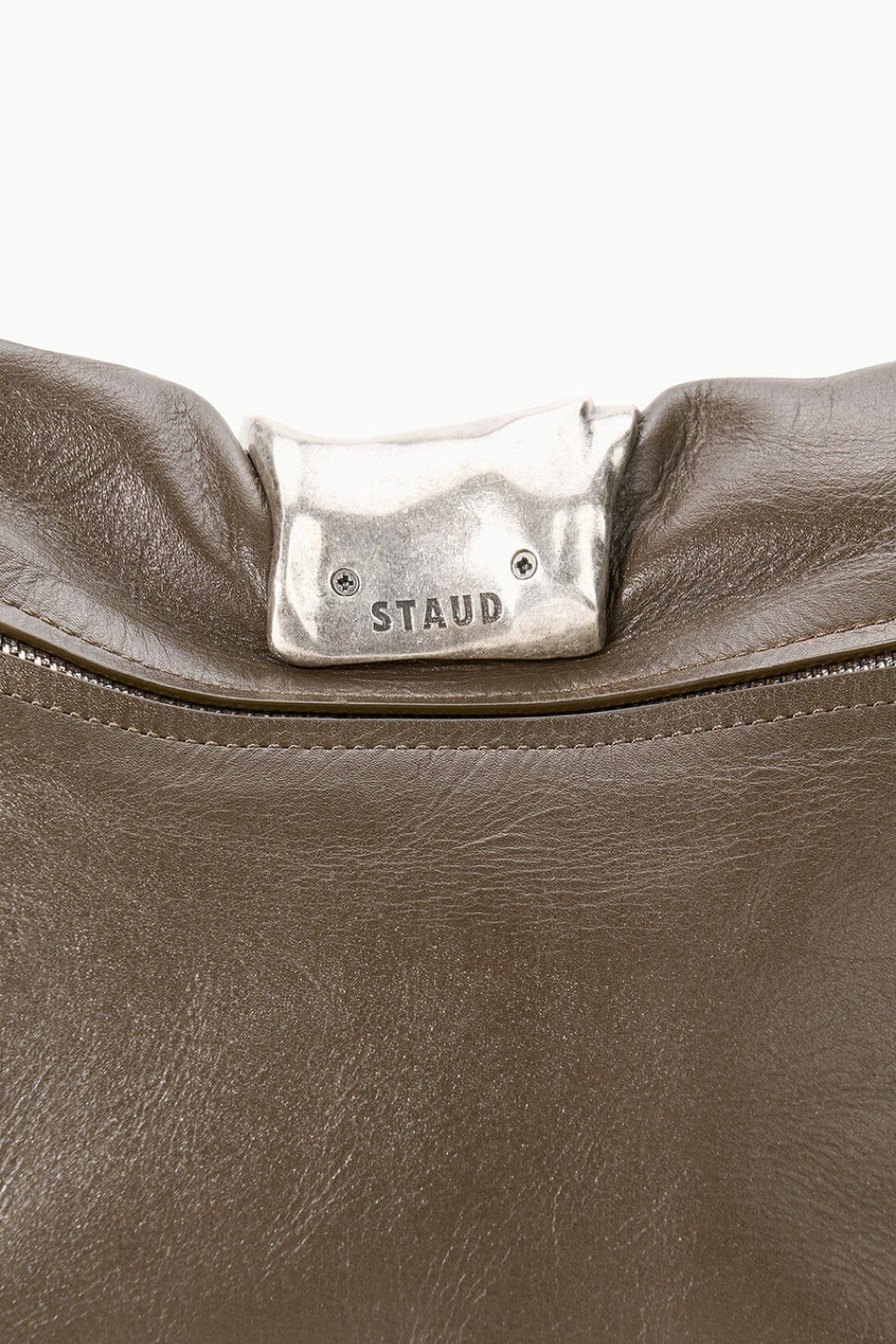 Close-up of a truffle leather bag with 'STAUD' logo on a white background