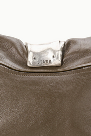 Close-up of a truffle leather bag with 'STAUD' logo on a white background