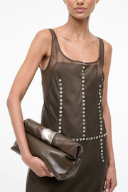 Woman wearing a brown dress with silver embellishments holding a truffle clutch.