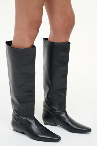 Black knee-high boots worn by a person on a white background