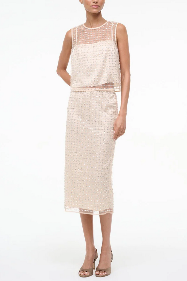 Woman wearing a two tone beaded top on a white background 