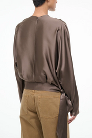 Person wearing a silk truffle colored and beige pants on a white background