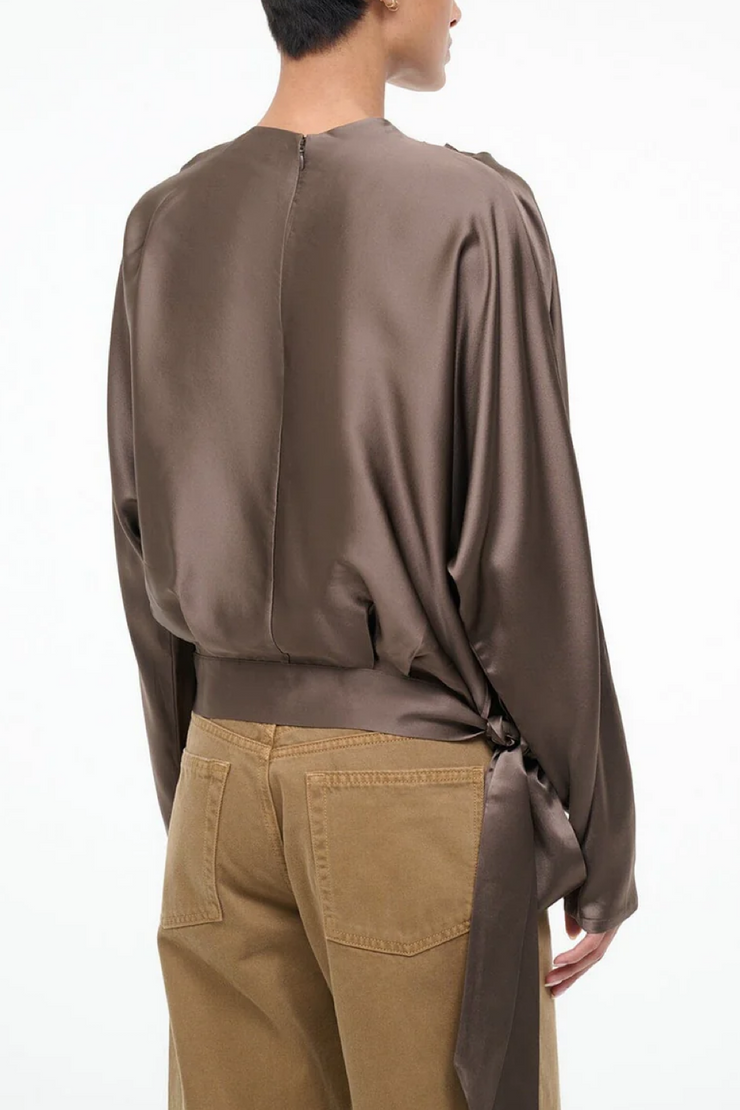 Person wearing a silk truffle colored and beige pants on a white background