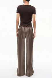 Person wearing a brown t-shirt and wide-leg silk truffle colored pants on a white background