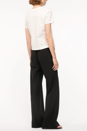 Person wearing a white top and black pants on a white background