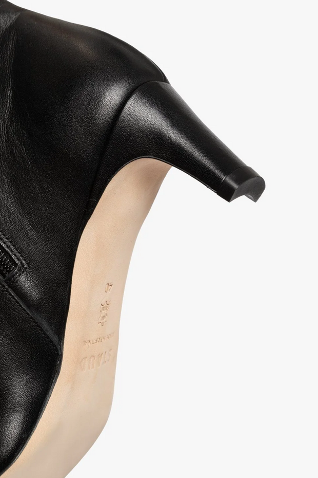 Black leather shoe with a pointed toe on a white background