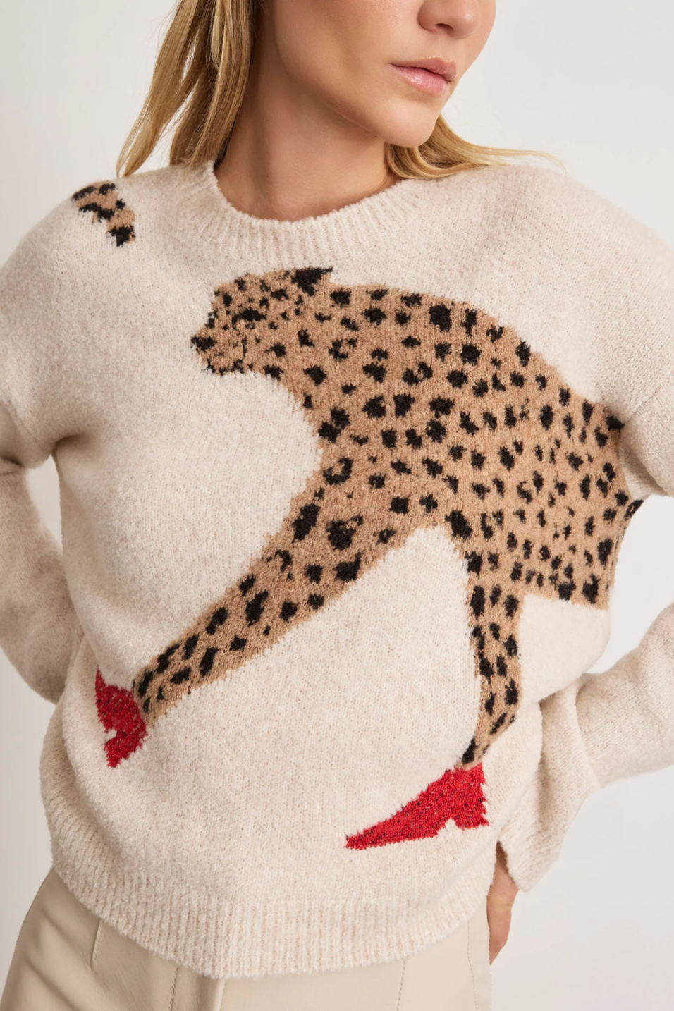 Beige sweater with a cheetah design worn by a person on a light background