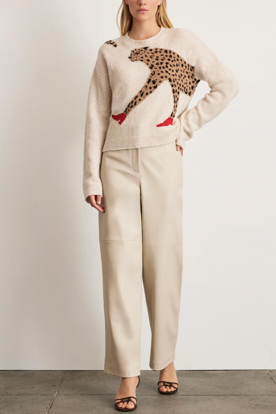 Woman wearing a beige sweater with a leopard print design and matching pants on a plain background