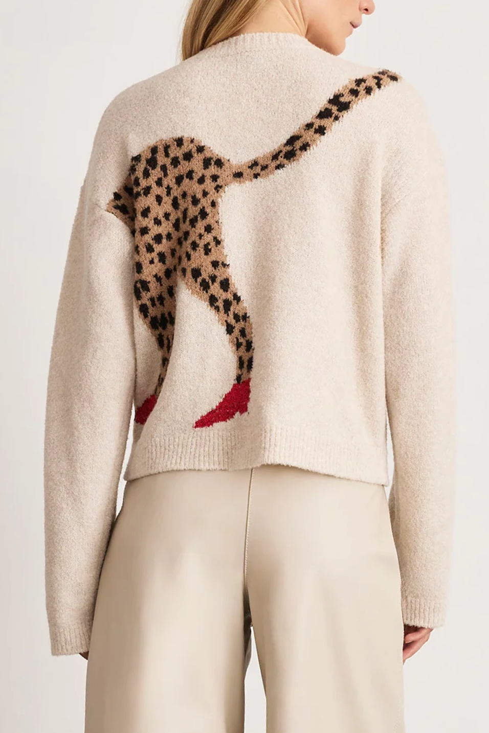 Beige sweater with a cheetah design on the back, worn by a person.