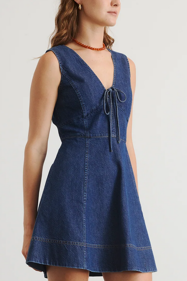 Woman wearing a blue denim dress against a plain background