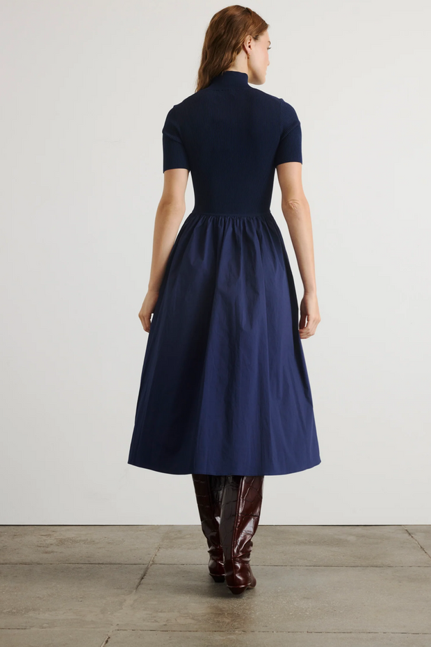 Woman wearing a navy blue dress with a plain white background